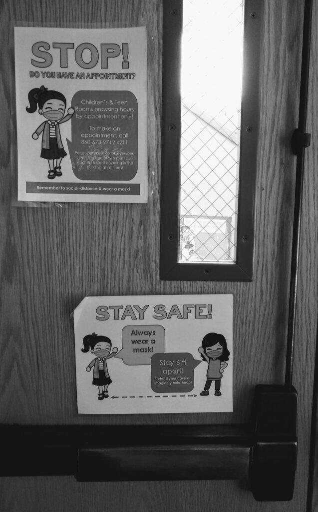 black and white photo of a door with with signs saying "Stop!" and "Stay safe!" with illustrated characters in face masks