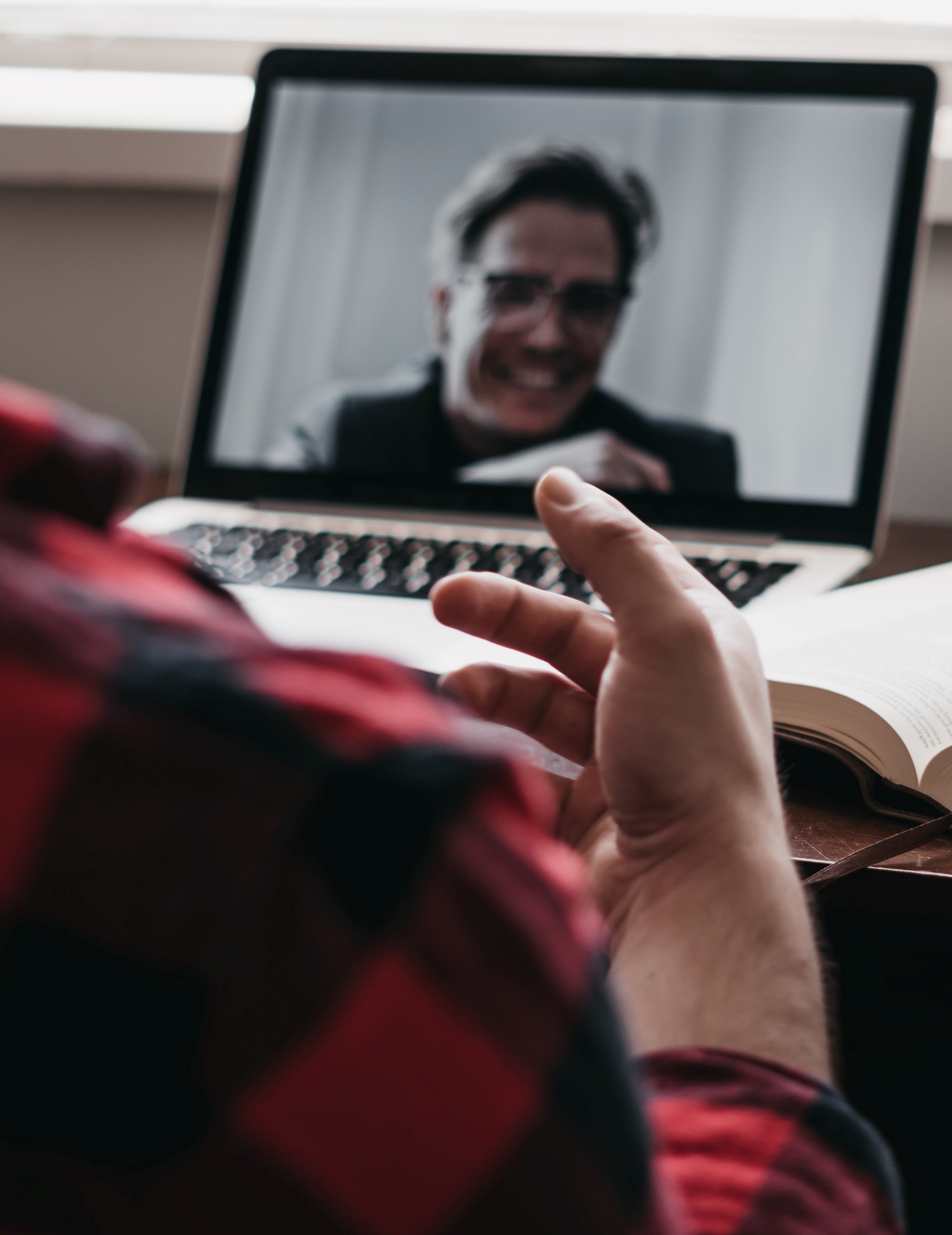 A person talking to a man on a laptop via Zoom.